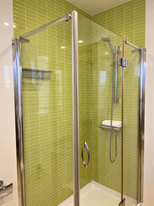 Moderno baño con mampara de cristal y paredes revestidas de azulejos verde lima en apartamento Aires de Baiona, Baiona, España