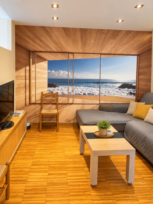 Moderno apartamento de madera en Baiona con vistas al océano, sofá, televisor y ventanales con vista al mar y olas de playa