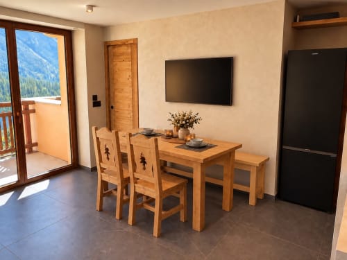 Salle à manger avec table et chaises en bois aux Tanières de Montgenèvre, vue sur les montagnes par la porte-fenêtre