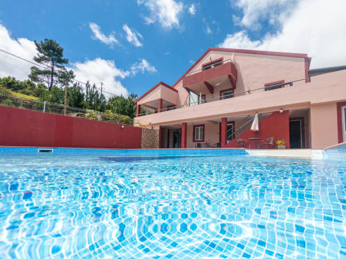 Modern pink apartment building with crystalline blue swimming pool at Quinta Frizado in Prazeres, Portugal