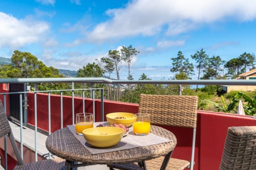 Terrace breakfast setup at Quinta Frizado in Prazeres with yellow bowls, orange juice, and mountain views