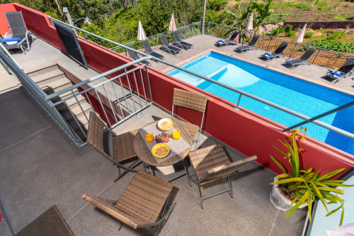 Poolside terrace at Quinta Frizado with dining setup, lounge chairs, and blue swimming pool overlooking Prazeres gardens