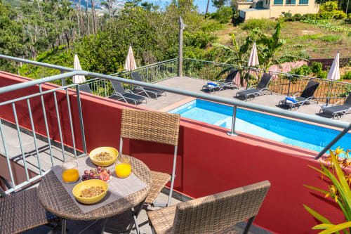 Terrace breakfast setup with yellow bowls overlooking blue pool at Quinta Frizado apartment in Prazeres, Portugal