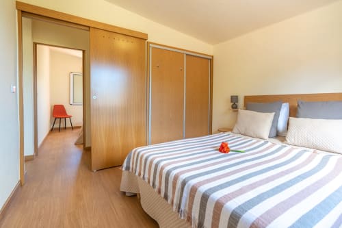 Bedroom at Garry's Holiday Rentals in Prazeres with striped bedding, wooden wardrobe, and access to living area