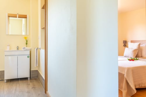 Modern bathroom with vanity and yellow walls connecting to bedroom at Quinta Frizado apartment in Prazeres, Portugal