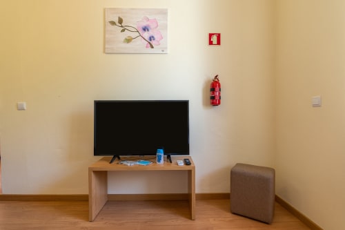 Modern apartment living area with flat-screen TV, wooden desk, brown ottoman, and wall decor at Garry's Holiday Rentals in