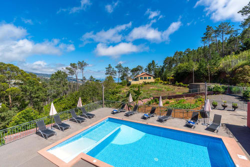Swimming pool with sun loungers at Garry's Holiday Rentals in Prazeres, Portugal, overlooking ocean and gardens