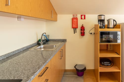 Compact kitchenette at Garry's Holiday Rentals with wooden cabinets, granite countertop, sink, microwave, and coffee maker.