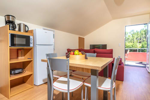Modern kitchen and dining area with wooden table, refrigerator, and microwave in Quinta Frizado apartment, Prazeres