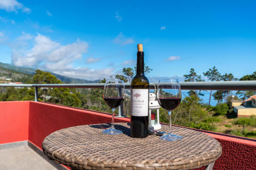 Wine glasses and bottle on terrace overlooking Prazeres gardens at Quinta Frizado apartment