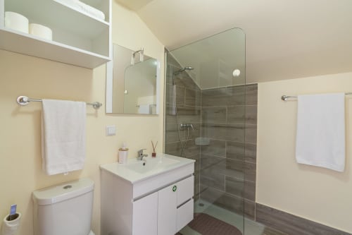 Modern bathroom at Garry's Holiday Rentals in Prazeres with walk-in shower, white vanity, and cream walls