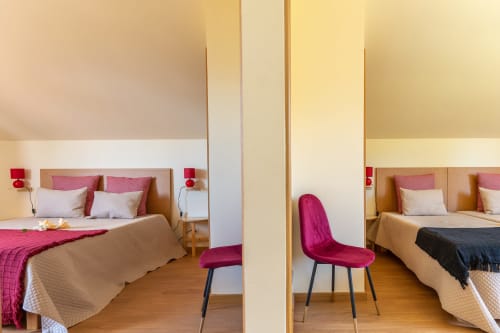 Modern bedroom at Garry's Holiday Rentals in Prazeres with twin beds, burgundy accents, and wooden flooring