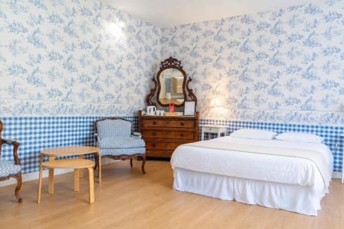 Chambre bleu et blanc à l'Hôtel Joly à Armentières avec lit, coiffeuse, fauteuil et mobilier en bois