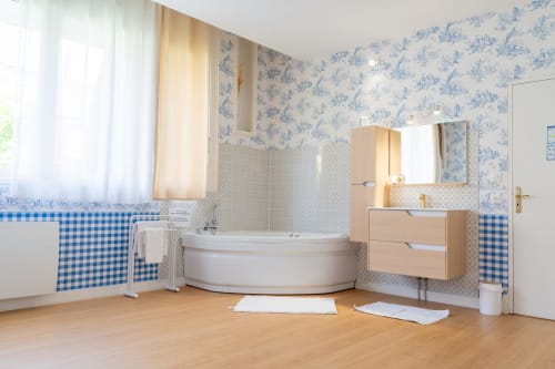 Salle de bains moderne de la Suite Madame Sans Gêne à l'Hôtel Joly d'Armentières, avec baignoire d'angle, meuble vasque en bois et toile bleue