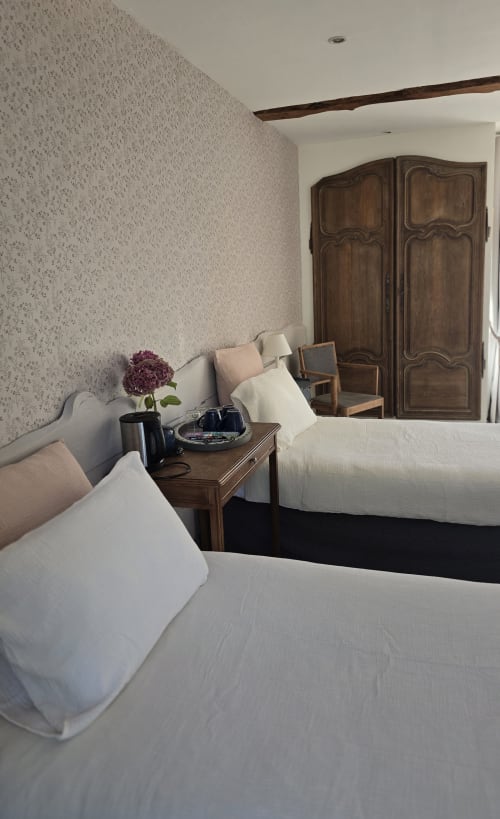 Elegant bedroom at Domaine de la Cour VAUTIER with twin beds, wooden wardrobe, and patterned wallpaper in