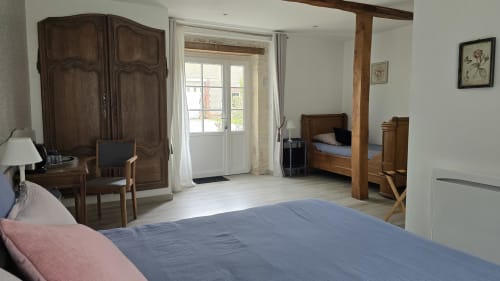 Spacious bedroom at Domaine de la Cour VAUTIER guesthouse with wooden beds, desk, and garden view doors