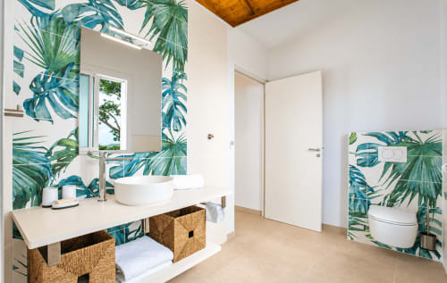 Salle de bain moderne avec papier peint tropical, vasque blanche, rangements tressés et toilettes à Villa Chanté Grenouilles