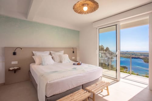 Chambre lumineuse de la villa Terrasses du Morne Gommier avec vue panoramique sur la mer, mobilier moderne et accès à la terrasse