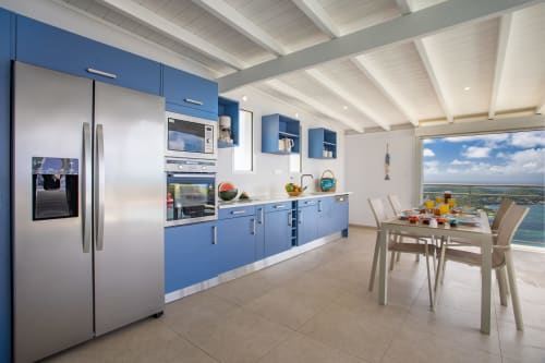 Cuisine moderne bleu et blanc avec appareils en acier inoxydable, salle à manger avec vue sur mer, Villa Nid des Colibris, Martinique