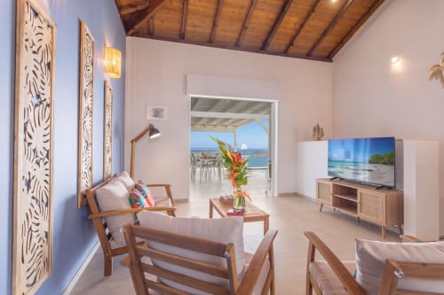 Salon de villa moderne avec vue sur mer aux Terrasses du Morne Gommier, mobilier en bois et accès à la terrasse océan