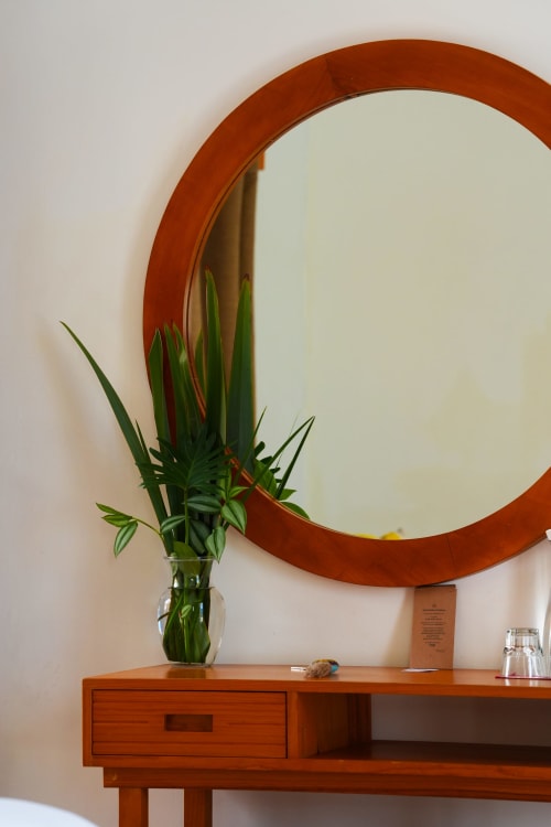 Consola de madera de mediados de siglo con espejo redondo en la Junior Suite de Casa Cafeólogo, San Cristóbal de las Casas, decorada con