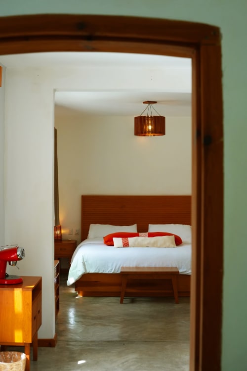 Habitación Junior Suite del hotel Casa Cafeólogo en San Cristóbal de las Casas con cama de marco de madera, ropa de cama blanca y detalles en rojo