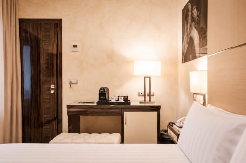 Camera standard di Maison Candia Roma con scrivania, lampada e vista sulla città dal letto