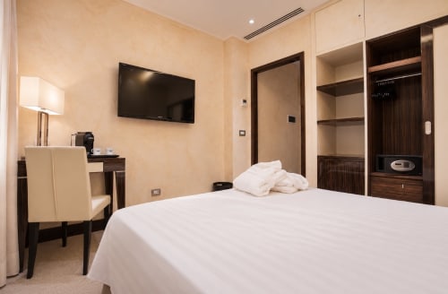 Camera moderna della Maison Candia Roma con letto queen size, TV a schermo piatto, scrivania e arredi in legno scuro