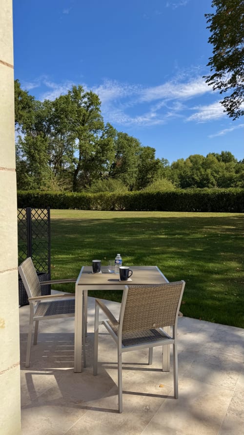 Terrasse extérieure du Cloffy BnB avec fauteuils en rotin, table et vue sur le jardin à Nouans-les-Fontaines