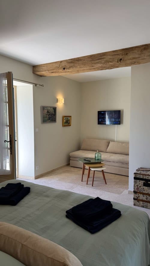 Chambre moderne de la Cloffy B&B avec poutre en bois, canapé crème, TV et porte vitrée ouvrant sur le salon