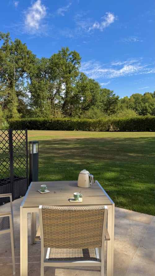 Coin détente sur la terrasse du Cloffy B&B à Nouans-les-Fontaines avec bouilloire, vue sur pelouse entretenue et lisière