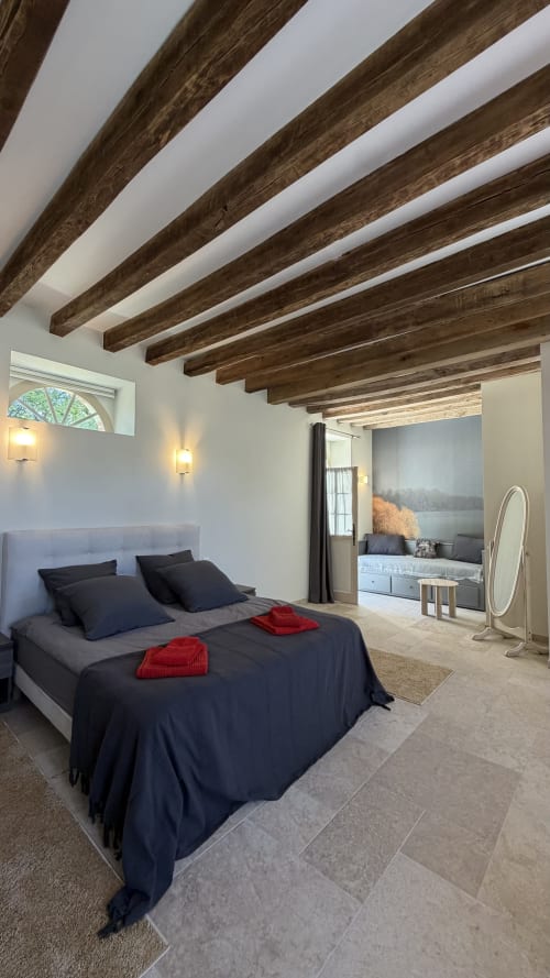 Modern bedroom at Cloffy B&B in Loire with exposed wooden beams, queen bed, lake view, and contemporary furnishings