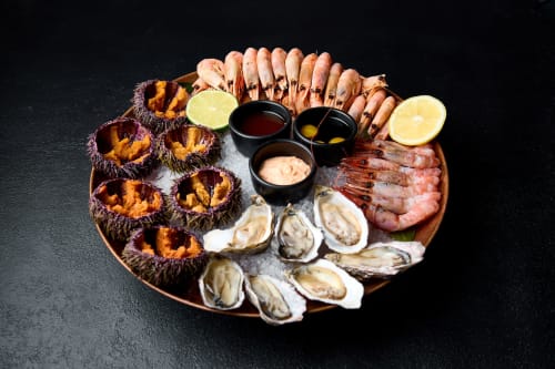 Luxurious seafood platter at L'Echappée Baie featuring sea urchins, oysters, prawns, and dipping sauces.