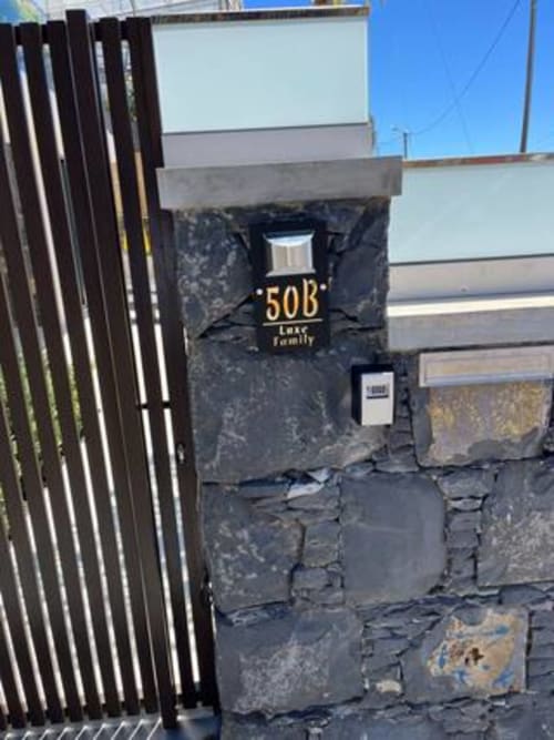 Entrada da villa familiar de luxo BHF Residences no número 50B em Arco da Calheta com fachada em pedra escura e iluminação solar