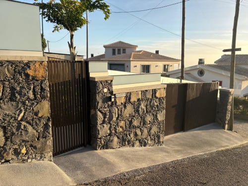 Entrada da villa moderna em BHF Residences Arco da Calheta com portão de pedra e metal escuro, arquitetura portuguesa visível