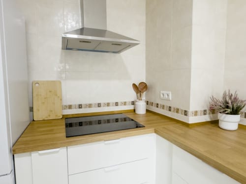 Cocina moderna en la casa rural Alzara de Living Sur, Sanlúcar de Barrameda con encimeras de madera, armarios blancos y acero inoxidable