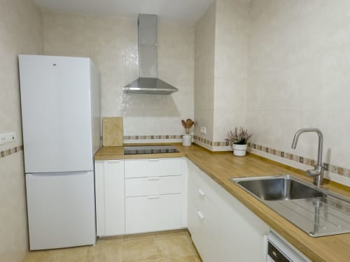 Cocina moderna en apartamento Alzara de Living Sur, Sanlúcar de Barrameda, con mobiliario blanco, encimeras de madera y