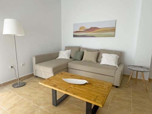 Sala moderna de la casita Alzara en Living Sur, Sanlúcar de Barrameda, con sofá beige, mesa de madera y vistas a la sierra