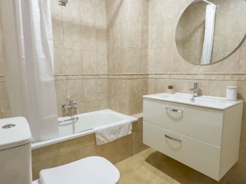 Baño moderno en tonos beige de la casita Living Sur en Sanlúcar de Barrameda con bañera, lavamanos y accesorios sanitarios