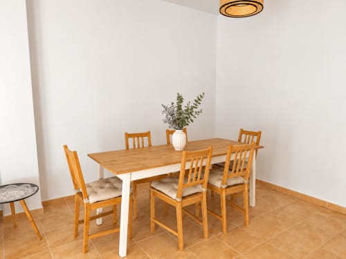 Comedor moderno en la casa rural Alzara de Living Sur, Sanlúcar de Barrameda, con mesa de madera, sillas y planta en maceta
