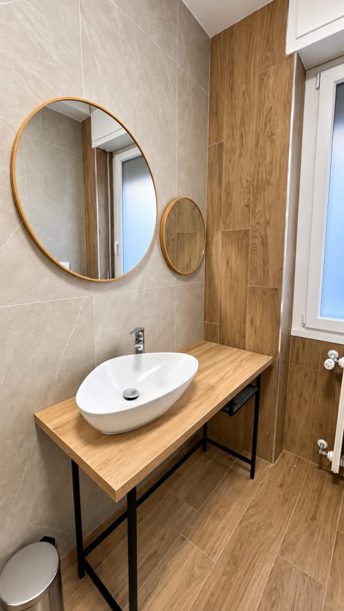 Bagno moderno dell'appartamento Tolstoi 13 a Saronno con lavabo bianco, mobile in legno e specchi rotondi