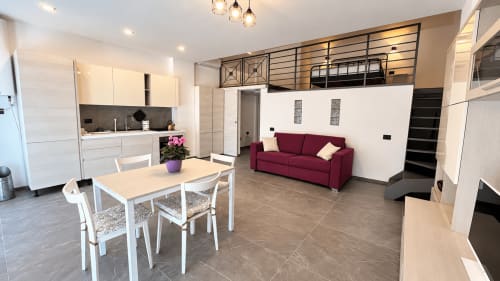 Moderno appartamento a Tolstoi 13 a Saronno con open-plan, divano bordeaux, zona pranzo, cucina bianca