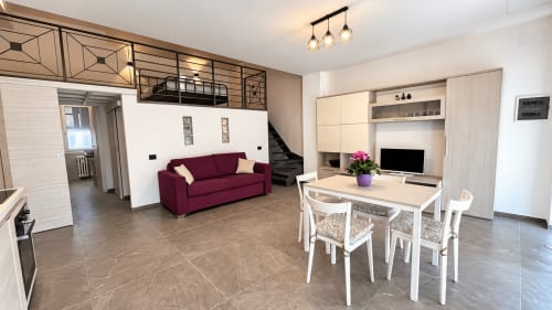 Moderno appartamento a Saronno con divano bordeaux, zona pranzo e centro intrattenimento con design accessibile e luce naturale