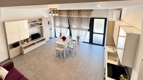 Moderna zona living a Saronno con tavolo da pranzo, angolo cottura, mobile TV e accesso balcone con porta in vetro