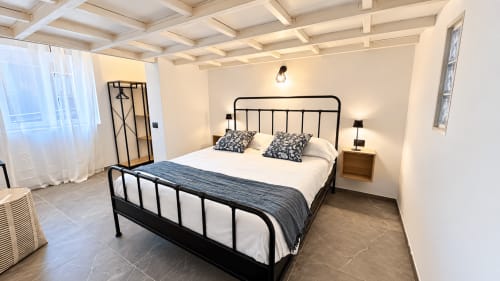 Camera moderna dell'appartamento Tolstoi 13 a Saronno con letto in metallo nero, biancheria bianca e vista sulla città