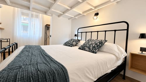 Camera moderna a Tolstoi 13.15 a Saronno con letto in metallo nero, biancheria bianca e vista sulla città