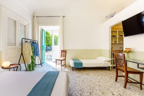 Spaziosa camera per ospiti al B&B Oliveri 25 di Procida con letti gemelli, porte con vista mare, TV e pavimenti in cotto