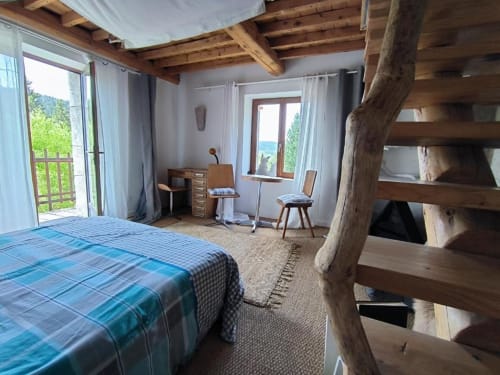 Chambre spacieuse à la Furanelle B&B à Saint Etienne avec literie à carreaux bleus, poutres apparentes, rangements rustiques et