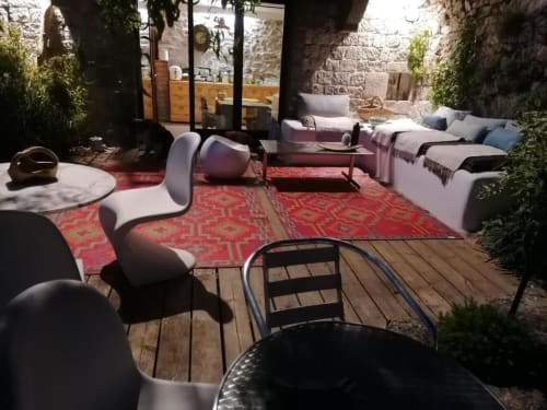 Cour Furanelle avec salon, tapis rouge, murs en pierre et lits à Saint Etienne