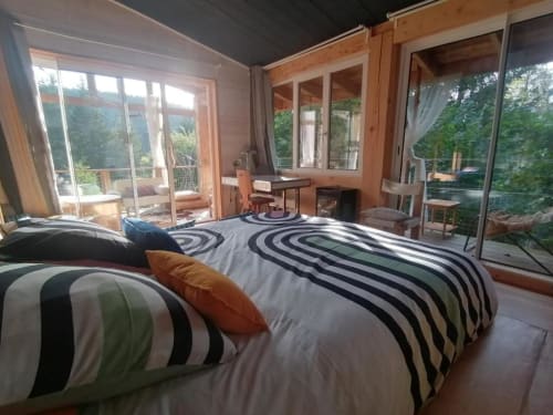 Chambre moderne de la Maison d'hôtes Furanelle à Saint Etienne avec literie rayée, mobilier en bois et vue panoramique sur la forêt